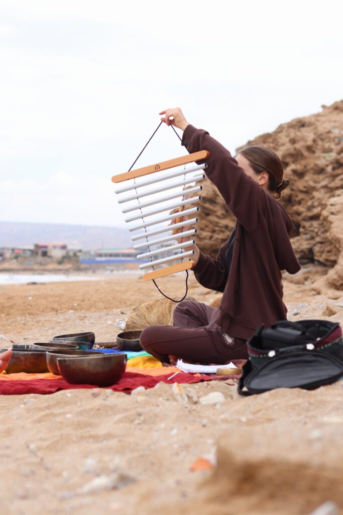Larissa playing sound chimes beside the sea.